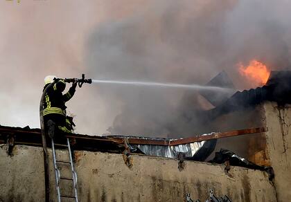 Esta foto tomada y difundida por el Servicio de Emergencia de Ucrania el 31 de julio de 2022 muestra a un bombero apagando un incendio en un edificio tras un bombardeo en Mykolaiv, en medio de la invasión rusa de Ucrania.