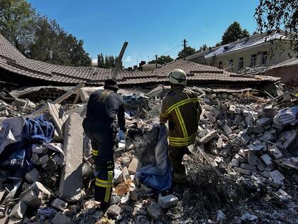 Esta fotografía de mano tomada y publicada por el Servicio de Emergencia de Ucrania el 27 de julio de 2022 muestra a los rescatistas limpiando los escombros de un edificio de hotel parcialmente destruido como resultado del ataque con misiles a Bakhmut, región de Donetsk, en medio de la invasión rusa de Ucrania. 