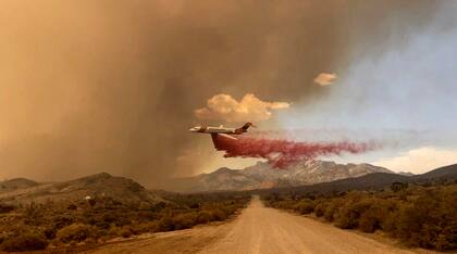Esta fotografía difundida por la Reserva Nacional de Mojave del Servicio de Parques Nacionales muestra un avión cisterna dejando caer retardante contra fuego sobre un incendio, el sábado 29 de julio de 2023, en la Reserva Nacional de Mojave (Guardaparque R. Almendinger/ InciWeb /Reserva Nacional de Mojave del Servicio de Parques Nacionales vía AP)
