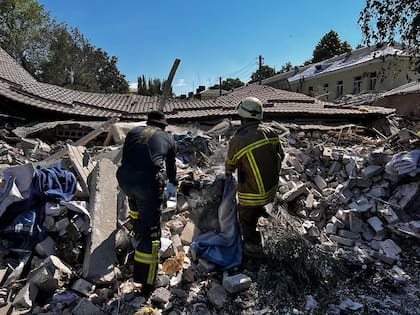 Esta fotografía publicada por el Servicio de Emergencia de Ucrania el 27 de julio de 2022 muestra a los rescatistas limpiando los escombros de un edificio parcialmente destruido como resultado del ataque con misiles a Bakhmut, región de Donetsk, en medio de la invasión rusa de Ucrania. 