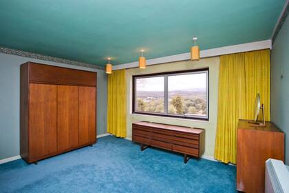 Esta habitación está equipada con un techo con estampado gráfico, gabinetes y algunas cortinas llamativas que combinan con los colores del techo y alfombra. Detalles puramente retro Foto: Matthews Benjamin