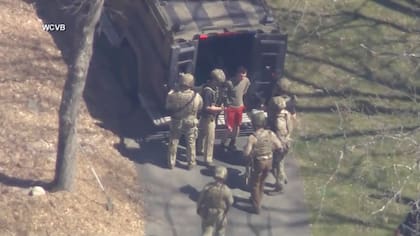 Esta imagen de video provista por WCVB-TV muestra a Jack Teixeira, en camiseta y pantalones cortos, detenido por agentes tácticos armados, el 13 de abril en Dighton, Massachusetts (WCVB-TV via AP)