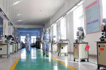 Esta imagen publicada por la Agencia Central de Noticias de Corea (KCNA) el 24 de enero de 2021 muestra a los empleados rociando desinfectante en la Fábrica de Productos de Higiene Dental de Pyongyang, en Corea del Norte