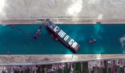 Esta imagen satelital de Maxar Technologies muestra el carguero MV Ever Given atrapado en el Canal de Suez cerca de Suez, Egipto, el domingo 28 de marzo de 2021. Dos remolcadores adicionales se dirigieron el domingo al Canal de Suez de Egipto para ayudar en los esfuerzos por liberar un buque portacontenedores del tamaño de un rascacielos encajados durante días a través de la vía fluvial crucial, incluso cuando los principales cargadores desvían cada vez más sus barcos por temor a que el barco tarde aún más en liberarse. (© Maxar Technologies vía AP)