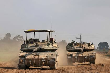 Esta imagen tomada desde una posición en el sur de Israel cerca de la frontera con la Franja de Gaza muestra carros de combate israelíes rodando a lo largo de la frontera en medio de las batallas en curso entre Israel y el grupo militante palestino Hamás. (Foto de Menahem KAHANA / AFP)