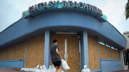 Estados Unidos: en Daytona Beach, estado de Florida, Miroslava Roznovjakova protege con bolsas de arena un local de ropa de playa cercano a la costa