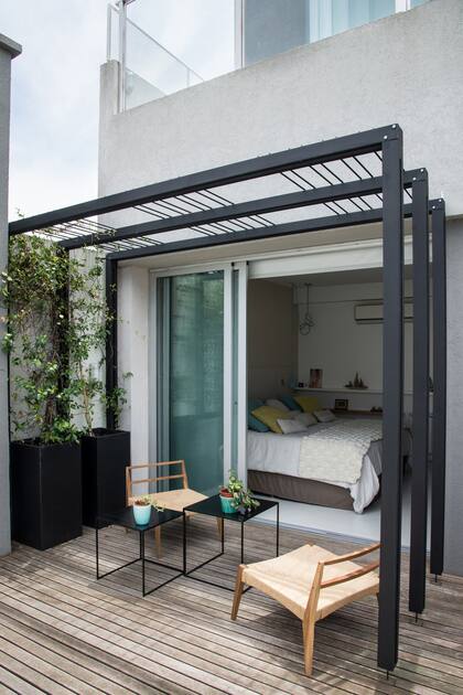 Este es un deck de madera en la planta baja de la casa que mira hacia el jardín. Cuenta con prismas de fibrocemento de 80 cm de altura, impermeabilizados por dentro, con Trachelospermum jasminoides.
La mesa negra es liviana y de chapa; las sillas se eligieron para que se puedan usar tanto adentro y como afuera de la casa.