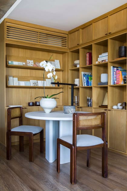 Este rincón está dedicado a su espacio de trabajo. Mesa circular ‘Appia’ con terminación gres de madera (Ascolta). Sillas (Un Lugar Así). Lámpara con base de piedra (La Feliz).