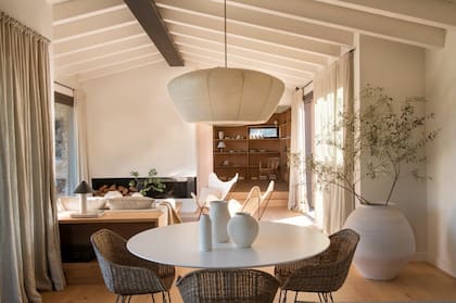 Este sector de la casa destaca por su estrecha relación con el exterior y por los techos inclinados de madera, pintados en un 'blanco roto' que potencia la luminosidad y genera una sensación inmediata de amplitud.