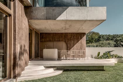 Este sector semicerrado comparte el menú de materiales del interior: hormigón teñido en las paredes, terrazo para la isla, hormigón blanco para el piso.