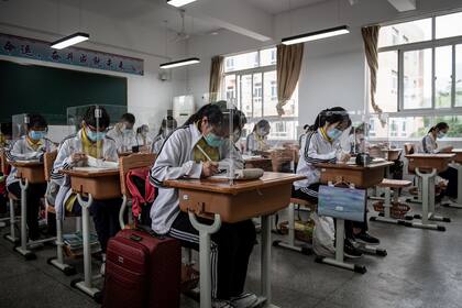 Estudiantes de secundaria protegidos contra el coronavirus en un aula en Wuhan, en la provincia central china de Hubei, el 6 de mayo de 2020