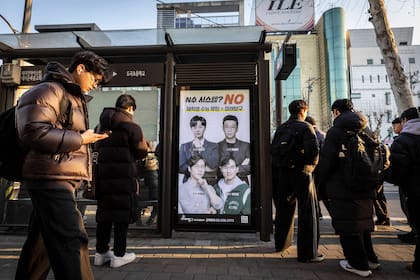 Estudiantes en una parada de autobús frente a un anuncio de instructores de una famosa hagwon, una academia privada de refuerzo extraescolar para niños, en Gangnam, una zona acomodada de Seúl