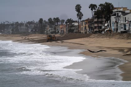 Excavadoras de la ciudad de Long Beach construyen un arcén de arena en preparación para la marea alta a lo largo de la península en Long Beach, California, el lunes 19 de febrero de 2024. (AP Foto/Damian Dovarganes)