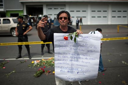 Un hombre cerca de donde lo asesinaron a Facundo Cabral sostiene una cartel en ciudad de Guatemala para pedir el esclarecimiento del crimen