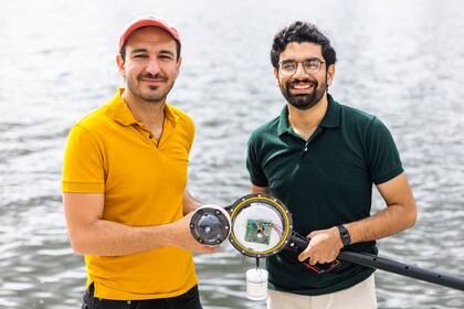 Fadel Adib (izq.) y Waleed Akbar (der.) muestran la cámara subacuática sin baterías que diseñaron en el MIT