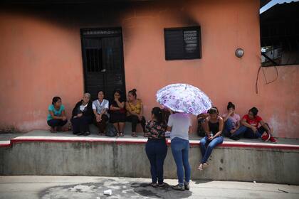 Familiares de 21 personas que fueron detenidas por integrantes del grupo de autodefensas "El Machete" aguardan en el porche de una casa incendiada por noticias de sus seres queridos