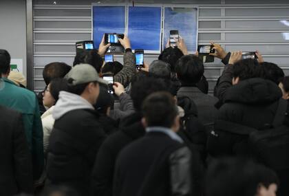 Familiares de las víctimas toman fotos de las listas con los nombres de los fallecidos en el accidente del avión en el Aeropuerto Internacional de Muan, en Corea del Sur, el 29 de diciembre de 2024