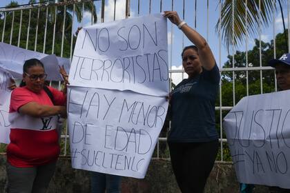 Familiares de los detenidos sostienen carteles afuera de la cárcel de Tocuyito donde están detenidos en Pocaterra, Venezuela, el lunes 26 de agosto de 2024