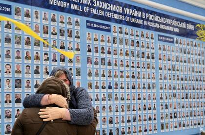 Familiares de los llamados Cyborgs, militares ucranianos que murieron durante la defensa del aeropuerto de Donetsk, se abrazan junto a un muro de la memoria de los militares caídos en la guerra ruso-ucraniana en el centro de Kiev, el 21 de enero de 2022