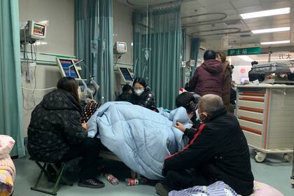 Familiares se reúnen junto a la cama de un paciente enfermo en el servicio de urgencias del Hospital Popular Langfang nº 4 de la ciudad de Bazhou, en la provincia septentrional china de Hebei, el jueves 22 de diciembre de 2022. 