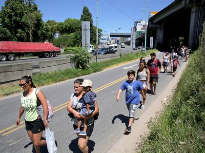 Familias caminan por la calle, entre los vehículos, hasta las playas de la Costanera Norte