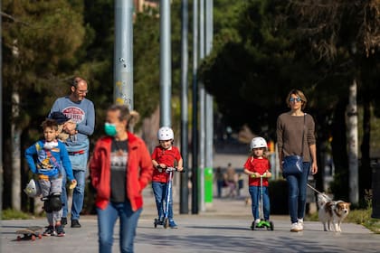 Familias caminan por un bulevar en Barcelona, España, el domingo 26 de abril de 2020, mientras continúa el bloqueo para combatir la propagación del coronavirus