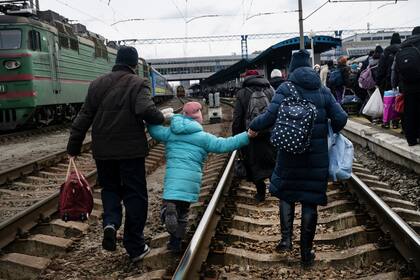 Las familias corren por las vías del tren para llegar al próximo tren que se dirige al oeste hacia Lviv, en la estación principal de trenes en Kiev