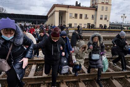 Mujeres y niños corren por las vías para llegar al siguiente tren que se dirige al oeste hacia Lviv, en la estación principal de trenes de Kiev, la capital de Ucrania