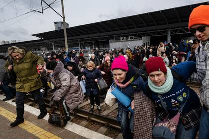 Las familias corren por las vías del tren para llegar al próximo tren que se dirige al oeste hacia Lviv en la estación principal de trenes en Kiev, 4 de marzo de 2022