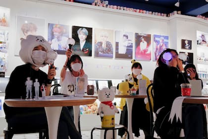 Fanáticos de BTS disfrutan mientras ven un concierto en streaming, con máscaras protectoras para evitar la propagación de la enfermedad del coronavirus en un café en Seúl, Corea del Sur
