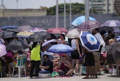 Fans de Taylor Swift se protegen del sol en Río de Janeiro.   (AP /Silvia Izquierdo)