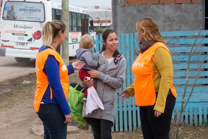 Fany, junto a otra de las voluntarias de El Arca, conversando con una vecina de la comunidad