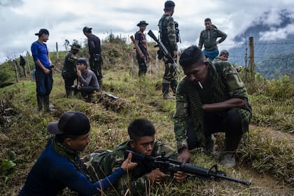 Dos integrantes de las viejas FAR le enseñan a un miembro de su bloque disidente a usar un rifle de asalto.