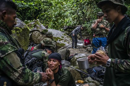 Un grupo de guerrilleros rebeldes de las FARC desayunan cerca de un arroyo.