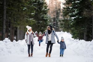 Father and mother with two small children in winter nature, walking in the snow.