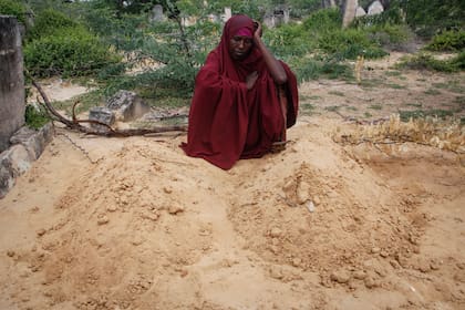 Fatuma Abdi Aliyow se lamenta junto a las tumbas de sus dos hijos muertos por enfermedades relacionadas con la desnutrición, en un campamento para desplazados, el 3 de septiembre de 2022, en las afueras de Mogadiscio, Somalia. (AP Foto/Farah Abdi Warsameh)