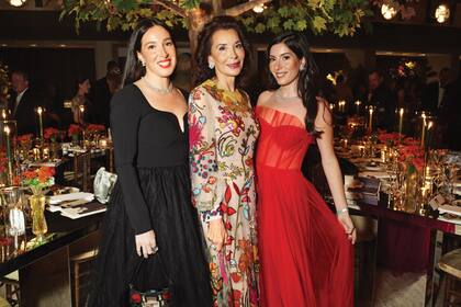 Fe Fendi (en el medio), junto a sus hijas Paola (a la derecha) y Alessia, con vestido rojo, bisnietas de los fundadores de la casa Fendi.