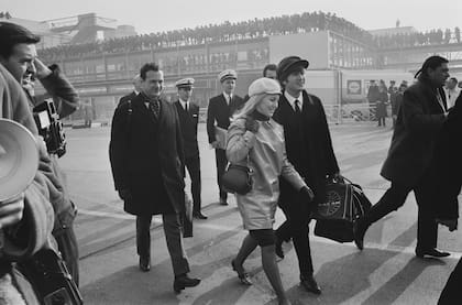 Febrero de 1964. The Beatles parten rumbo a Estados Unidos. John Lennon y Cynthia Powell caminan de la mano por la pista del aeropuerto de Londres. Detrás de ellos va Brian Epstein, manager de la banda.  (Photo by Stan Meagher/Express/Hulton Archive/Getty Images)