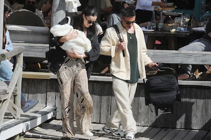 Felices los tres. María Guadalupe lleva a su hijo Vittorio en brazos después de almorzar en La Huella, mientras Pocho carga con el asiento y la mochila con las cosas del bebé.