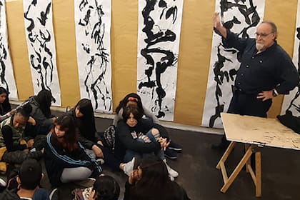 Fernando Fazzolari con un grupo de jóvenes estudiantes y sus tintas de grandes dimensiones