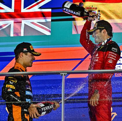 Festejo entre amigos: Lando Norris (McLaren) y el ganador Carlos Sainz Jr. (Ferrari) en el podio de Singapur; excompañeros de equipo, se ayudaron mutuamente para terminar al frente en el clasificador