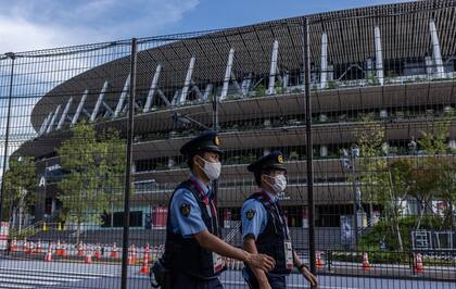 Oficiales de policía con máscaras patrullan junto al Estadio Olímpico de Tokio el 21 de julio de 2021 en Tokio.