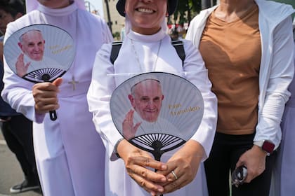 Fieles equipadas con abanicos con la cara del papa Francisco esperan en el exterior de la sede de la Conferencia Episcopal de Indonesia para saludar al papa, antes de una reunión, en Yakarta, Indonesia, el 5 de septiembre de 2024. (AP Foto/Tatan Syuflana)