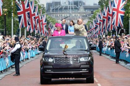 FIESTA ESPECIAL. Junio de 2016. Acompañada por su marido, Felipe, su nieto William y su mujer, Kate, y su nieto Harry, la Reina es aclamada por una multitud en su llegada al Almuerzo Patronal, una enorme fiesta callejera para homenajearla cuando cumplió 90 años.