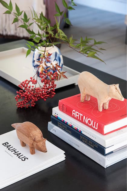 Figuras de madera (7&diez), libros de arte (Lasarte Bookstore) y bandeja (GHC Home Basics) con jarrón de cerámica (Del Mar).