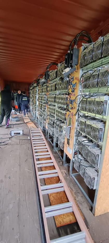 Filas de dispositivos ASIC con ventiladores gemelos y cableado artesanal para sostener la operación