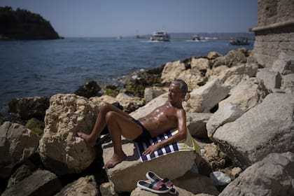 FILE - A man sunbathes in high temperatures in Marseille, southern France, Aug. 19, 2023. UN weather agency says Earth sweltered through the hottest summer ever as record heat in August capped a brutal, deadly three months in northern hemisphere. (AP Photo/Daniel Cole, File)�
