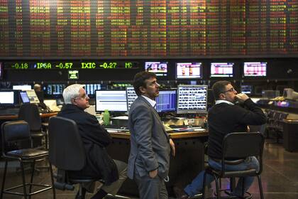 (FILES) In this file photo taken on June 18, 2018, traders look at a screen at the Buenos Aires Stock Exchange. - The Merval index of the Argentine stock market ended a 10-round bullish streak on Wednesday January 18, 2023 with a fall of 9.73% to 235,372.41 points, which analysts attribute to profit-taking after government announcements of a bond repurchase in Dollars. (Photo by EITAN ABRAMOVICH / AFP)