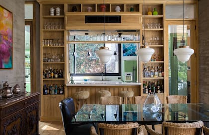 Florero de vidrio soplado (Estudio Ilusión). Junto a la ventana pasaplatos, banquetas de Leder.