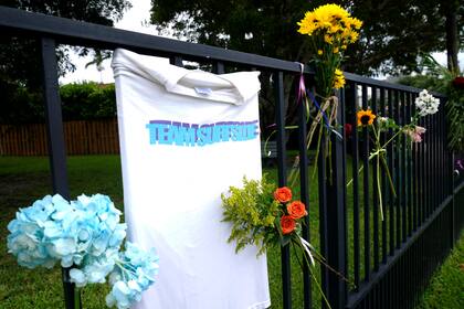 Flores y una remera en una reja cercana al lugar del siniestro en Surfside en homenaje a los muertos y desaparecidos del derrumbe 